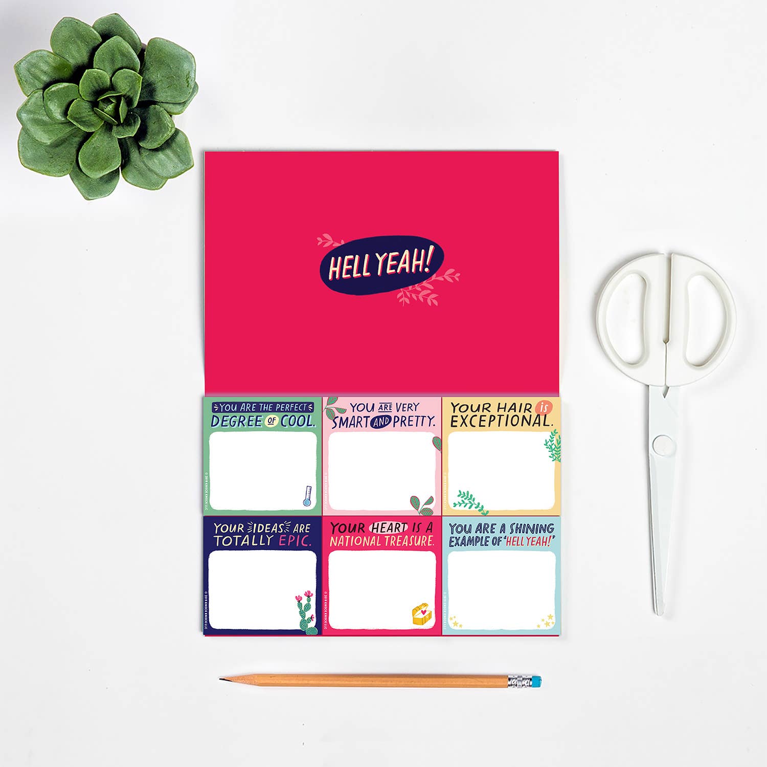 Sticky note packet featuring six pads with 40 sheets each, alongside a pink calendar, pencil, plant, scissors, colorful cards, frames, and a sign.