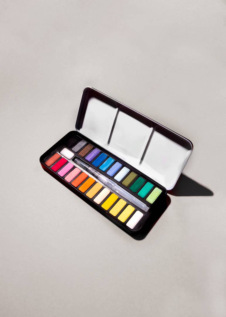 Watercolor paint kit featuring a box of paints and close-ups of a paint palette. Ideal for watercolor discovery, with a brush compartment for easy water filling.