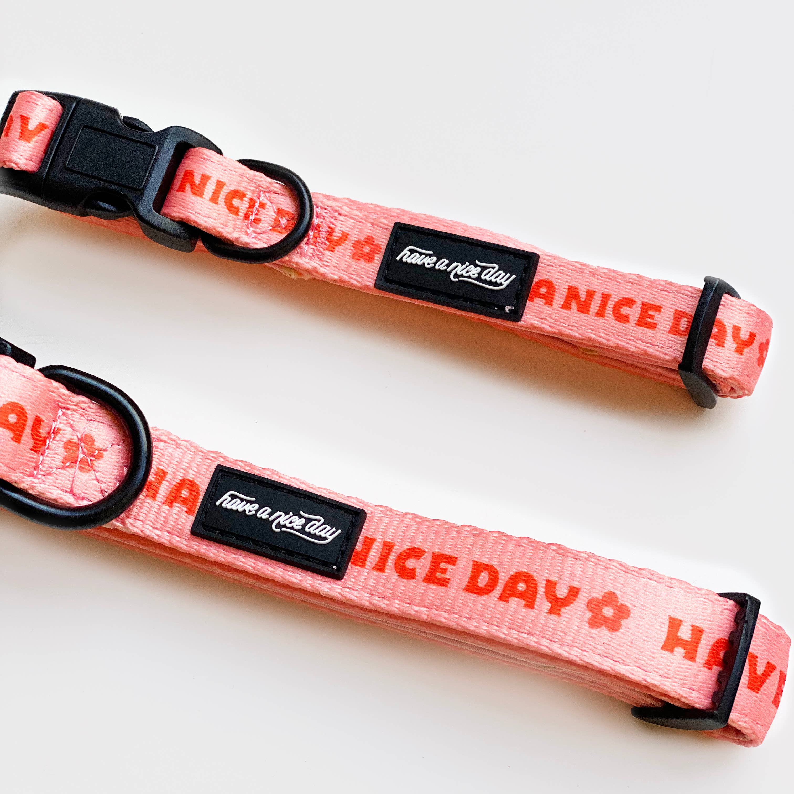 A pink nylon dog collar with Have a Nice Day print, black plastic clip, and metal ring. Available in XS to Medium sizes.