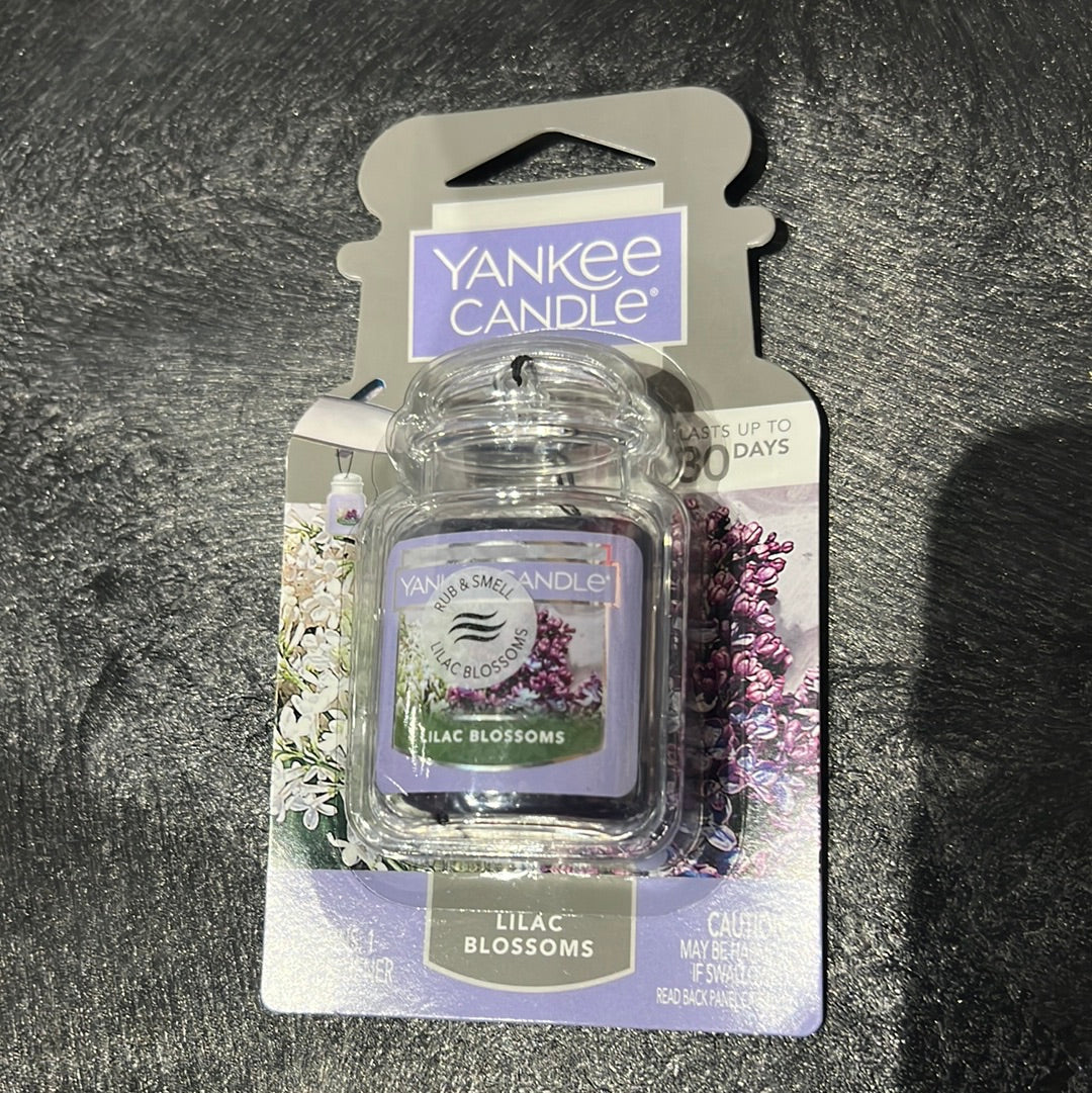 A close-up of Yankee Candle Gel Jar Air Freshener - Lilac Blossoms packaging with a jar and label detail, featuring purple flowers.