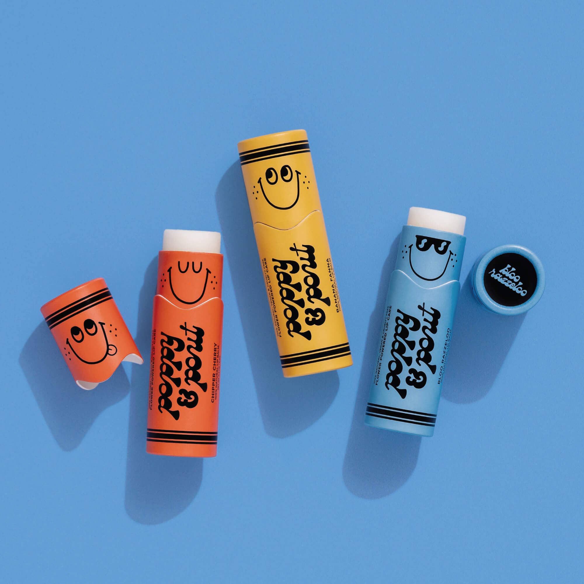 Close-up of Lil' Poppies Bloo Razzeloo lip balm tube with a face, part of a vibrant, kid-friendly collection.