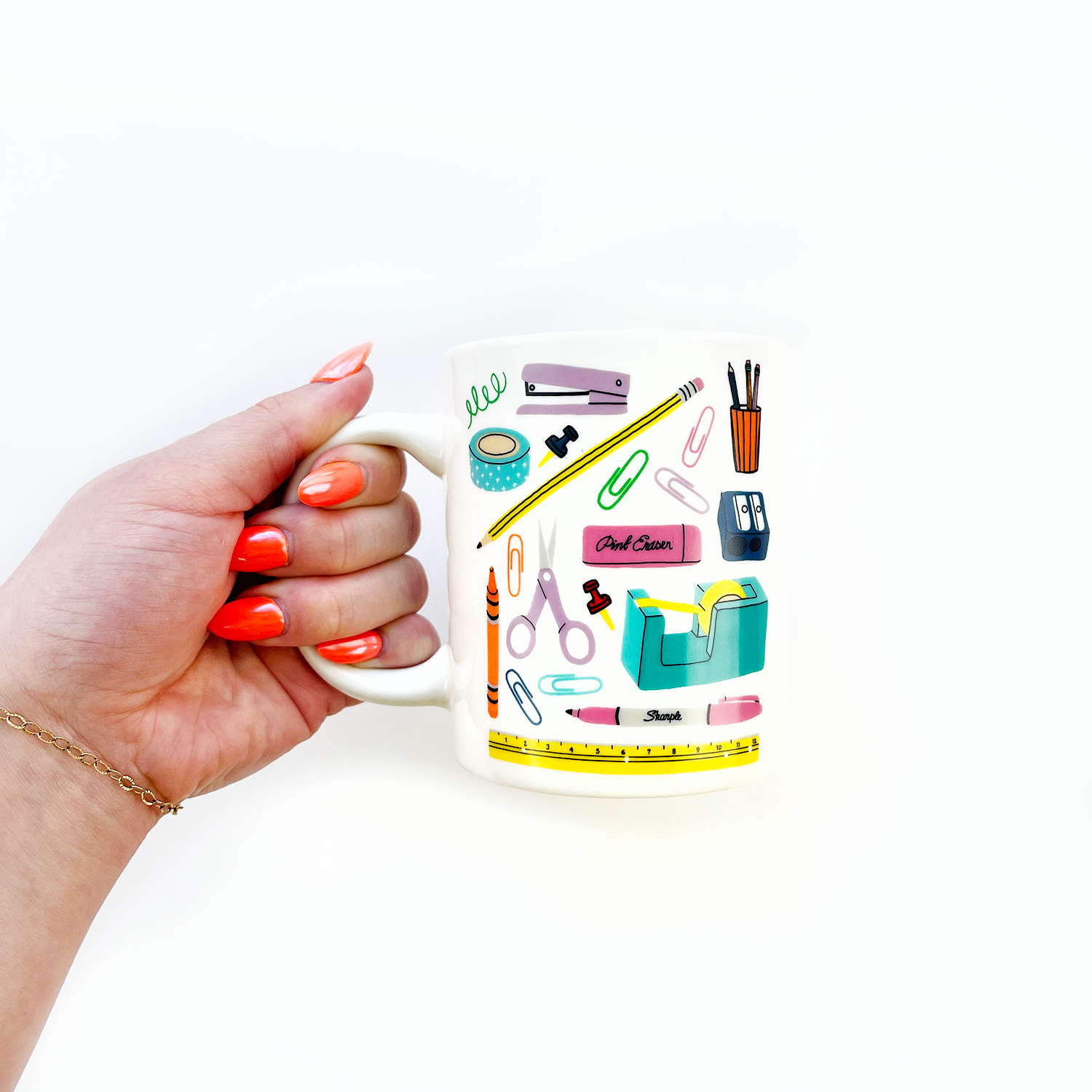 A hand holds a stationery-themed mug with exclusive designs, featuring a sticker motif. Microwave and dishwasher safe, 11oz capacity. Includes Pipsticks Stationery Aisle mug and matching vinyl sticker.