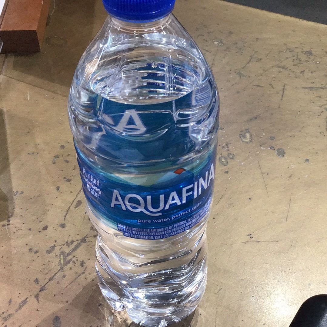 A close-up of Aquafina 16.9oz plastic water bottle on a table, showcasing the brand label and cap.