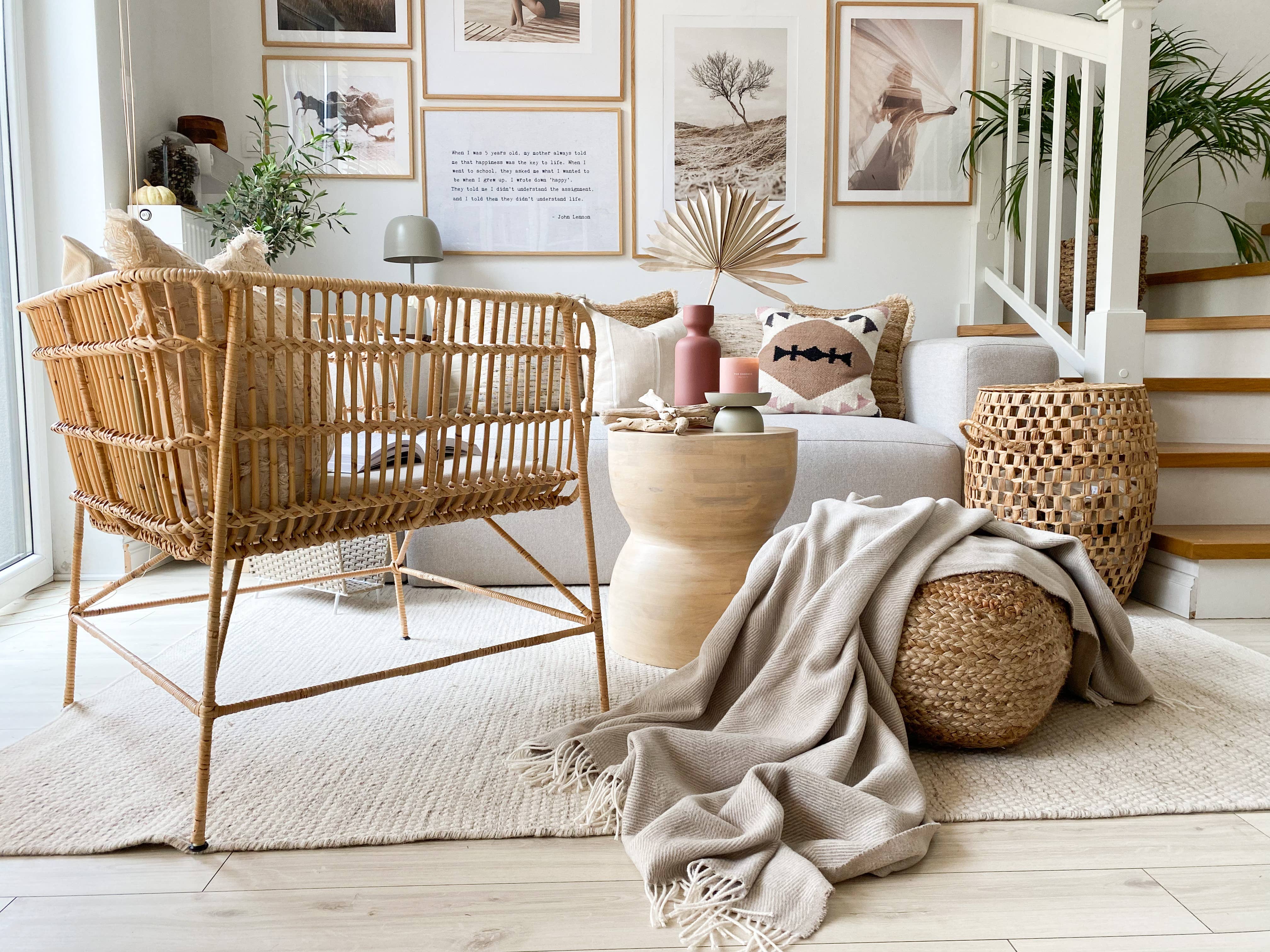 Elegant Herringbone Sand blanket in a stylish living room setting with wicker crib, pink vase, lamp, and pillow. Made in Italy from recycled materials for comfort and durability.