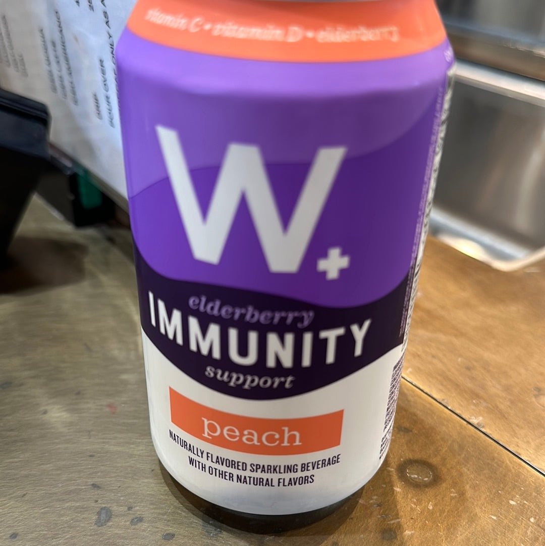 A close-up of a W immunity Peach beverage can with a white cross logo, featuring a purple label and a distinct logo design.