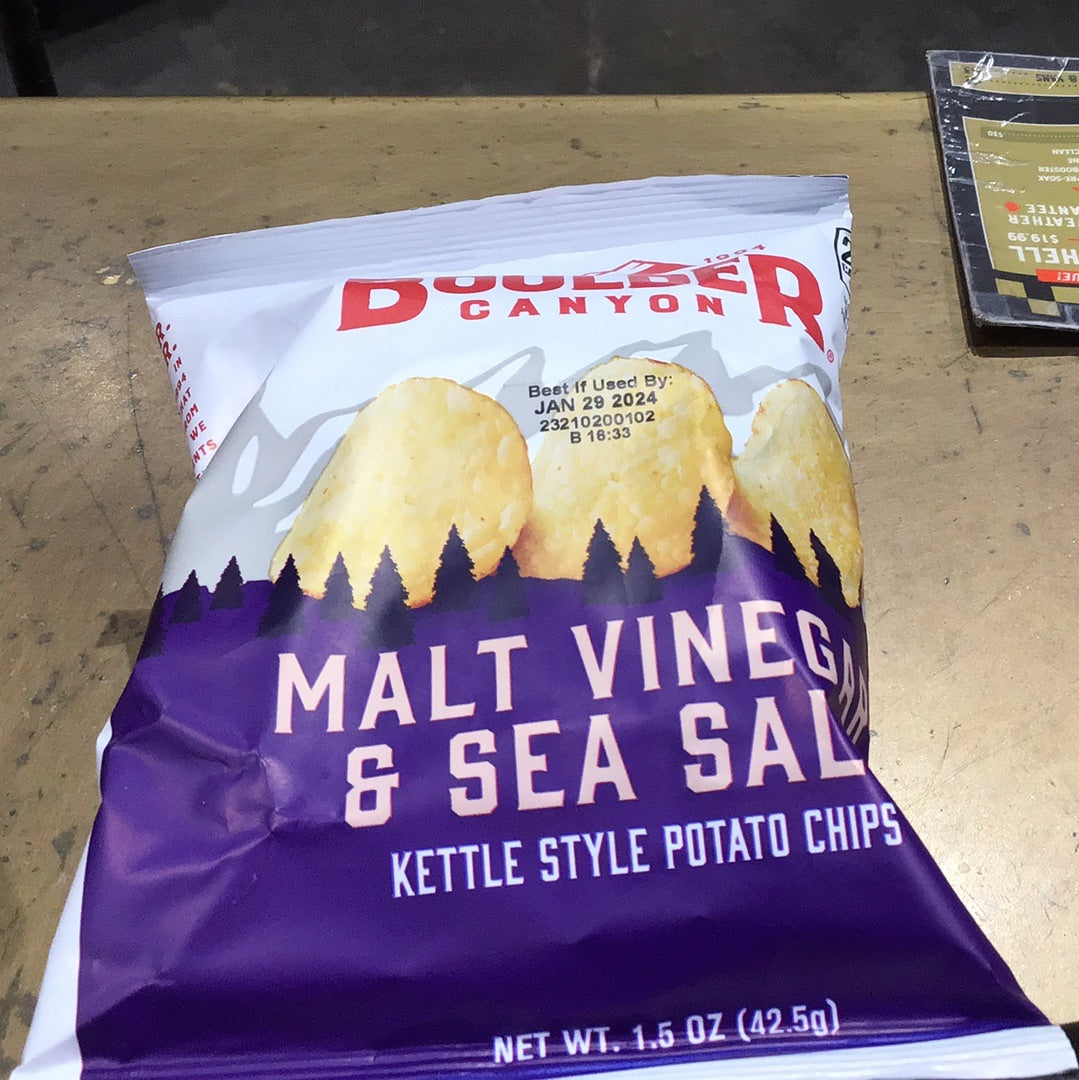 A close-up of Boulder Chips Malt Vinegar & Sea Salt bag, showcasing a single potato chip, with a red and white lettering detail.