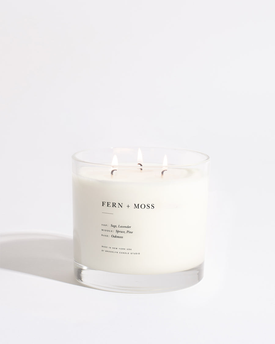 Maximalist 3-Wick Candle in Fern + Moss scent, 27 oz. Hand-poured in Brooklyn. White candle with three lit wicks in a screenprinted glass tumbler.