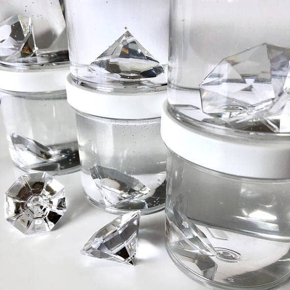 A group of clear plastic containers with Diamond Clear Putty Slime, featuring a diamond-shaped object and iridescent rhinestones. Perfect for poking and bubble pops.