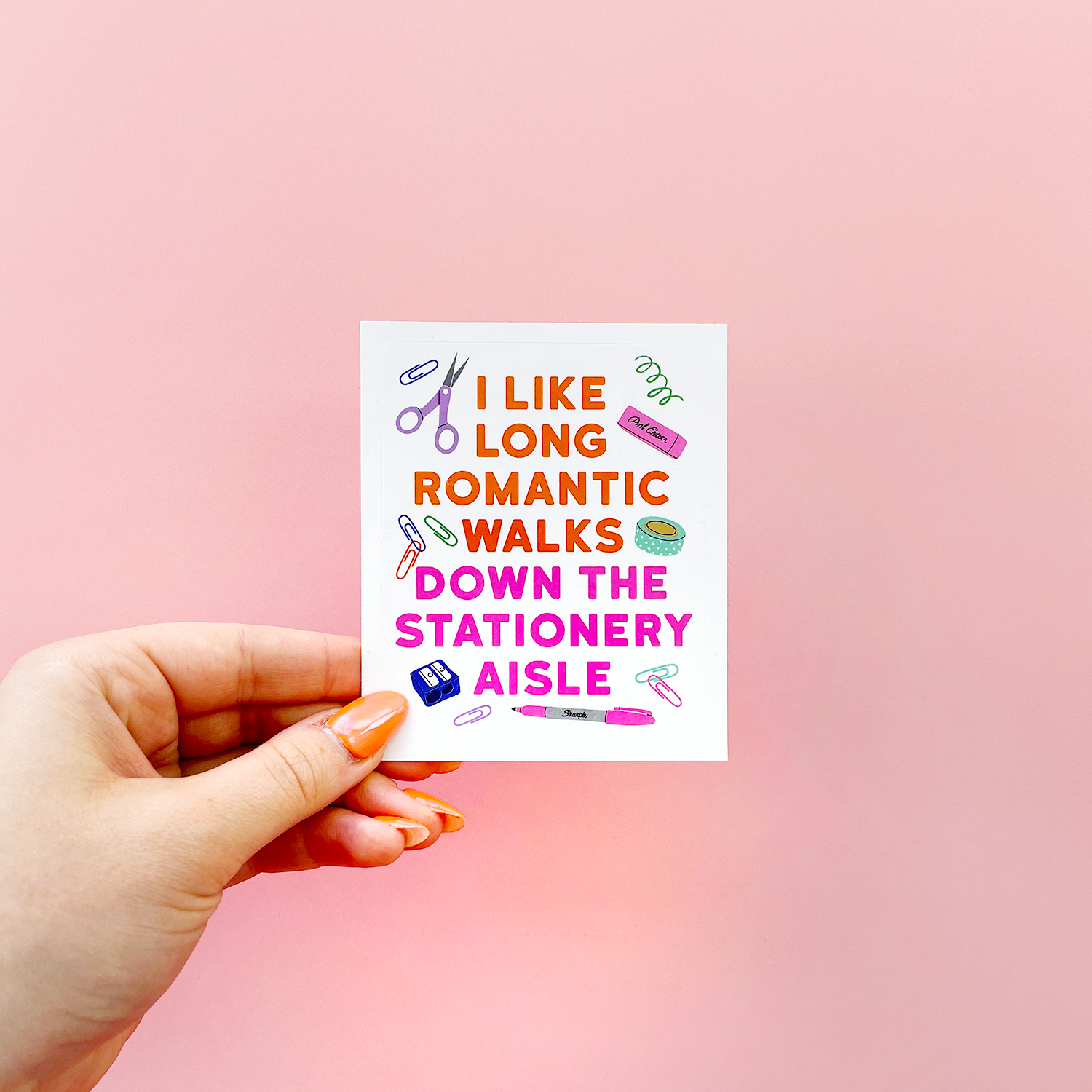 A hand holding a card with a Stationery Aisle Mug design and a matching vinyl sticker, perfect for sticker enthusiasts. Microwave and dishwasher safe, 11oz capacity.