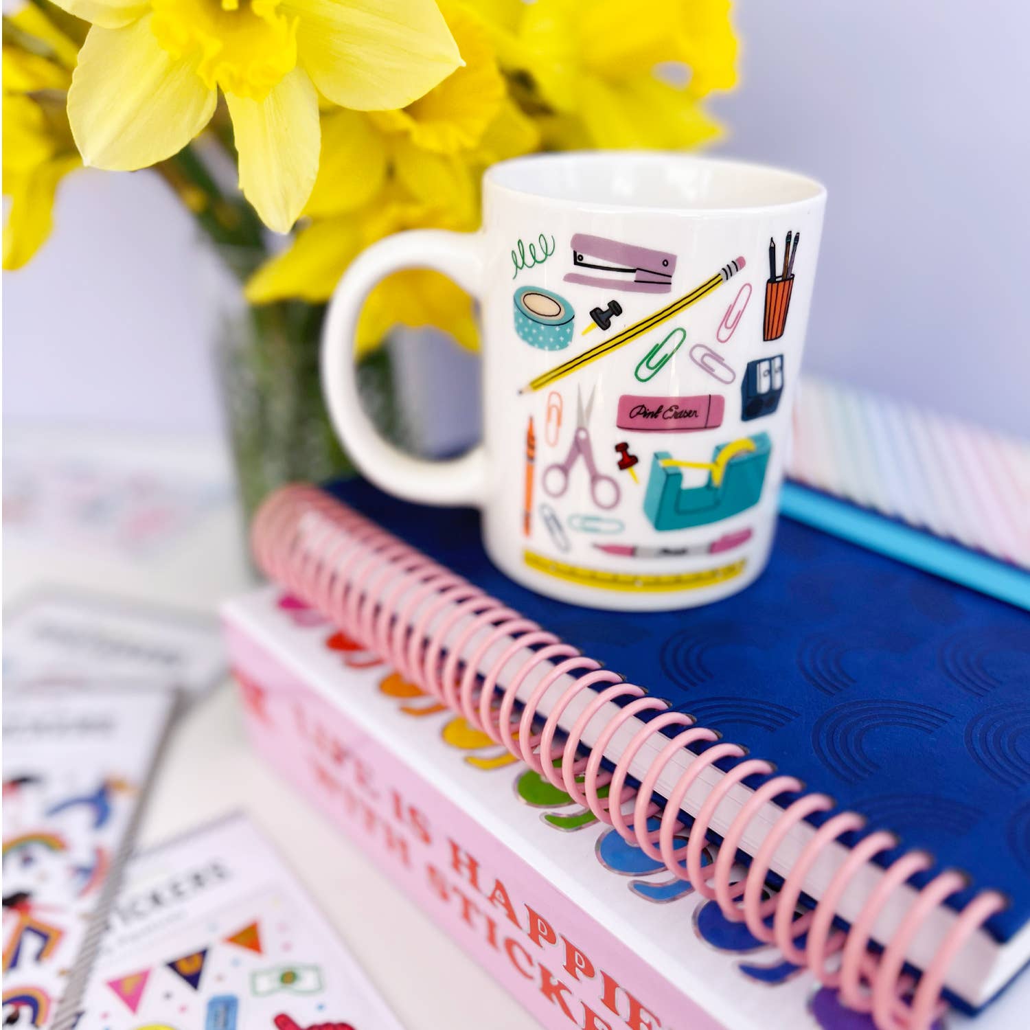 A white mug featuring stationery-themed design, stickers, and a notebook with flowers. Microwave and dishwasher safe, 11oz capacity. Includes Pipsticks Stationery Aisle mug and matching vinyl sticker.