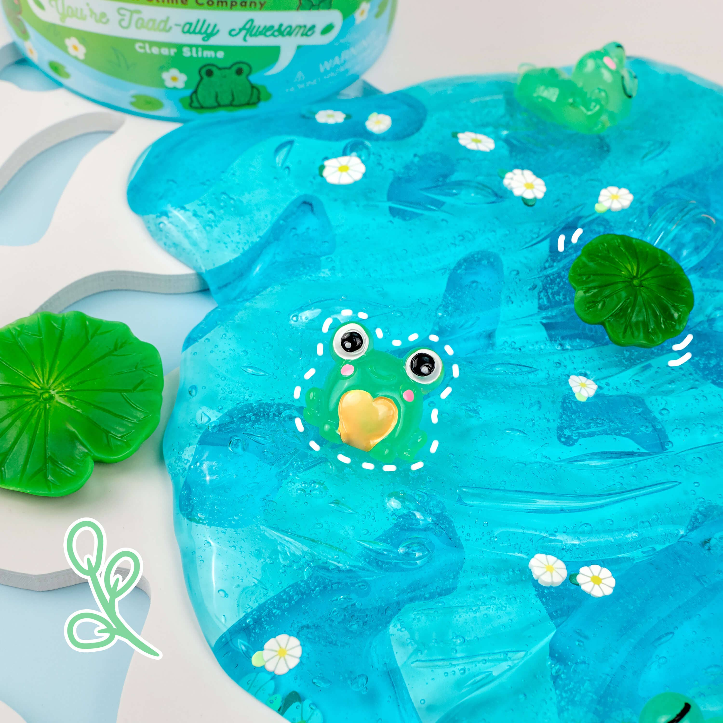 A clear slime with a frog face charm and a water lily scent, featuring a thick, stretchy texture for satisfying playtime.