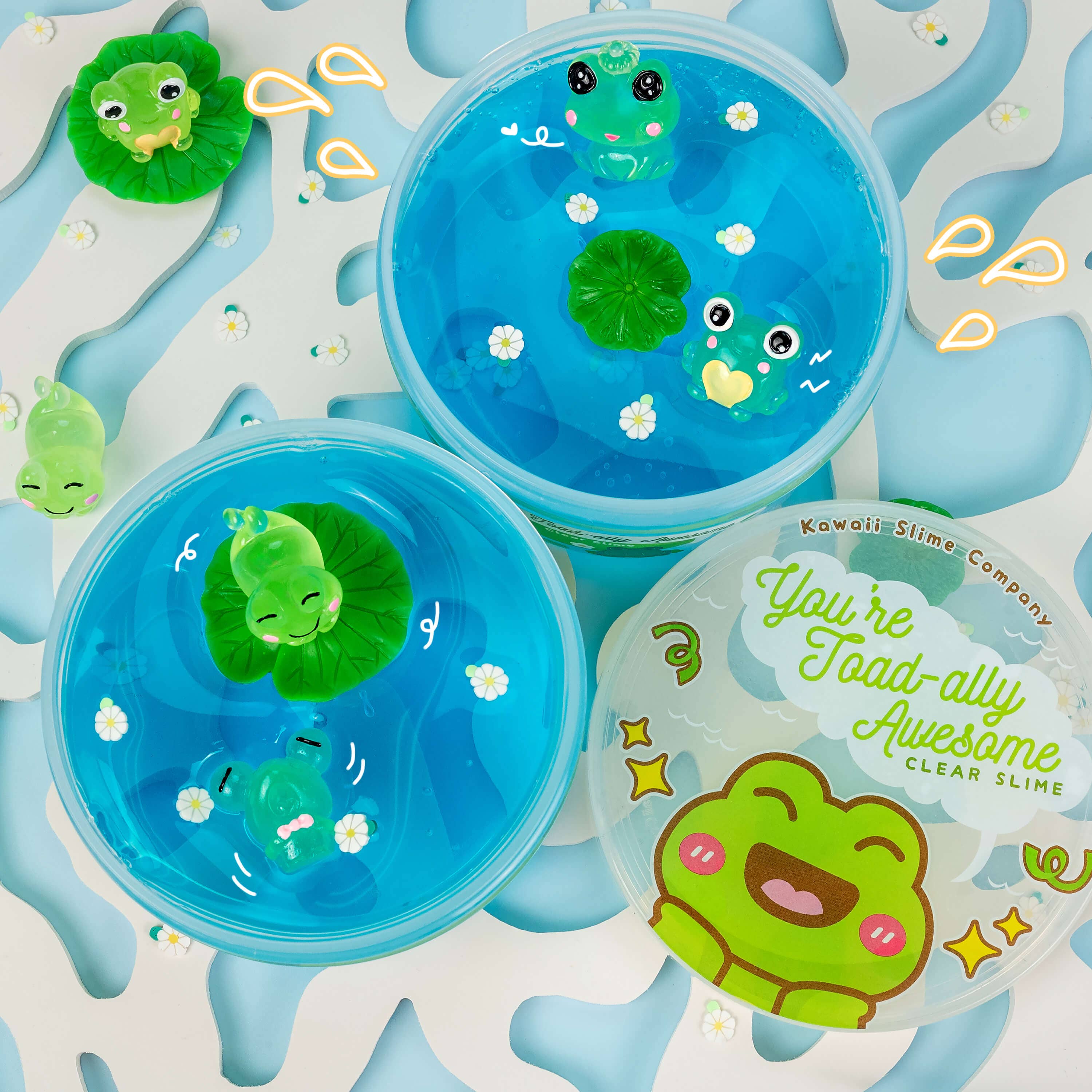 Four plastic containers of clear slime with green frog toys, a cartoon frog design, and lily pad accents. Includes two toad charms for stretchy, playful fun.