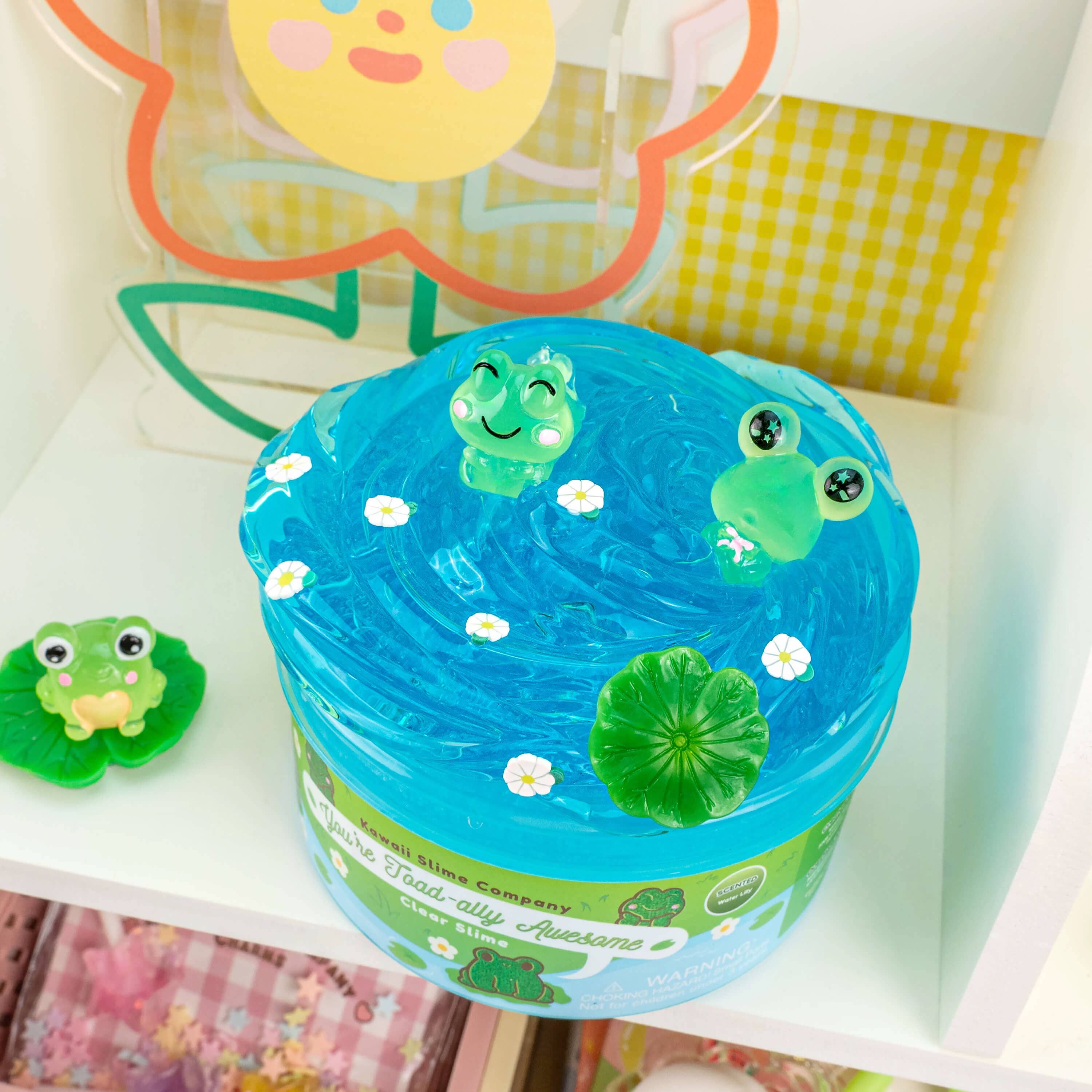 Four clear slimes with toad charms, featuring a water lily scent and bright blue color. Thick and stretchy texture for playful pokes and bubble pops.