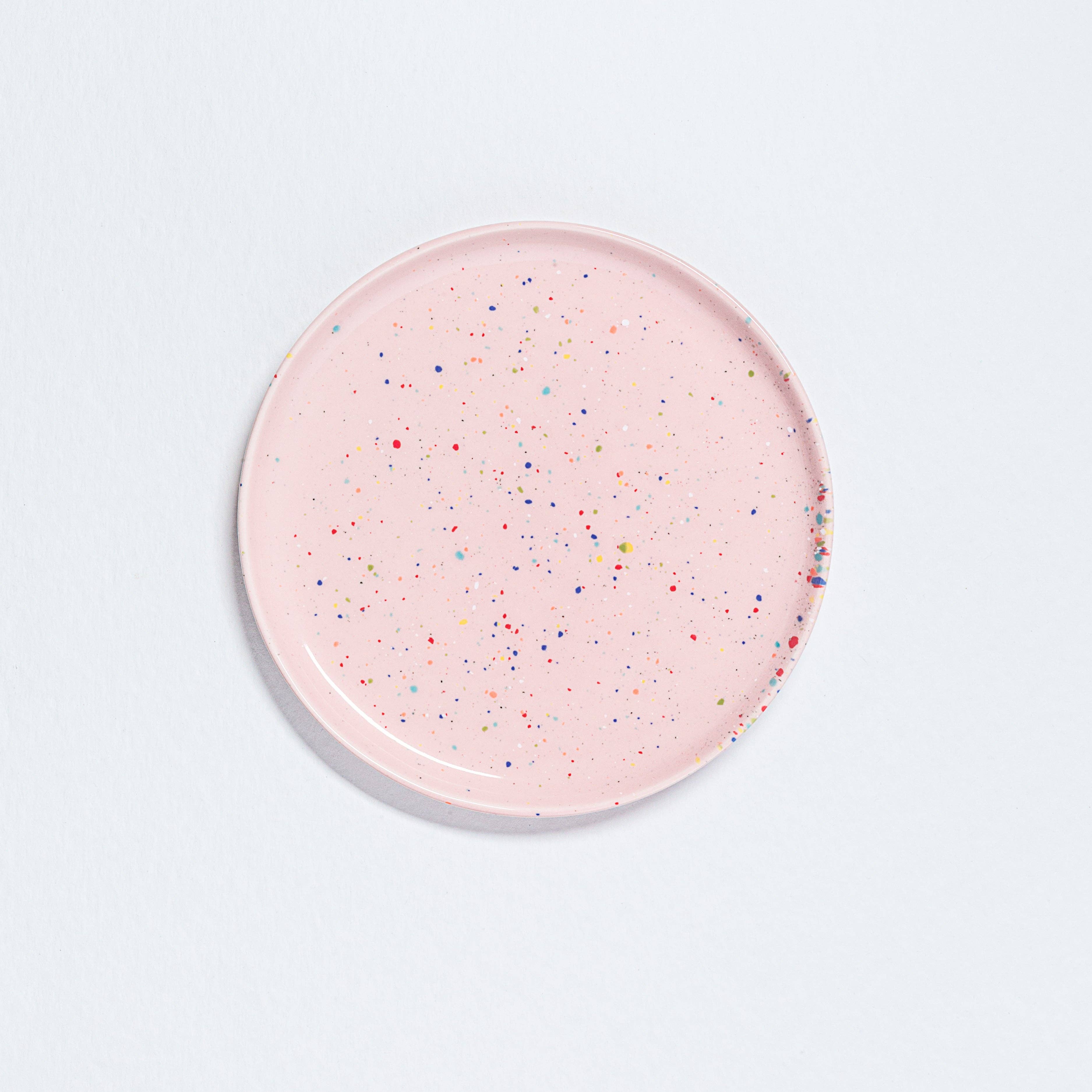 A pink salad plate with multicolored speckled spots, 22.5cm diameter, 1.5cm height. From the Party collection, dishwasher and microwave safe, food safe, and cadmium free. Crafted uniquely with vibrant design.