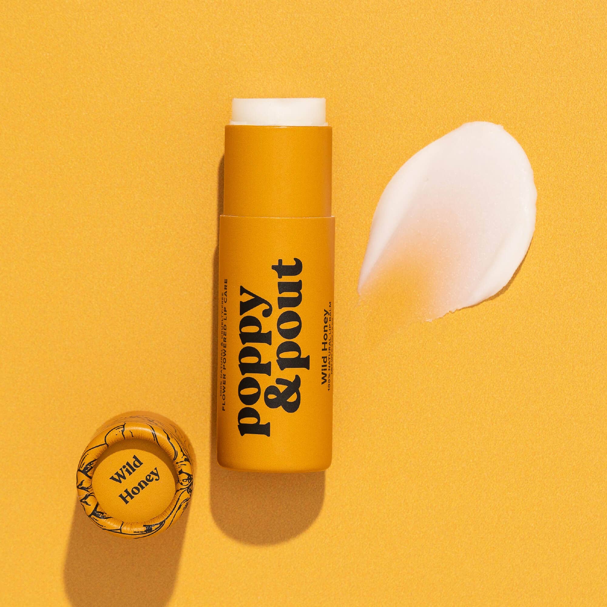 Hand-poured Wild Honey Lip Balm in eco-friendly tube on yellow background, emphasizing 100% natural ingredients and cruelty-free certification by Leaping Bunny.