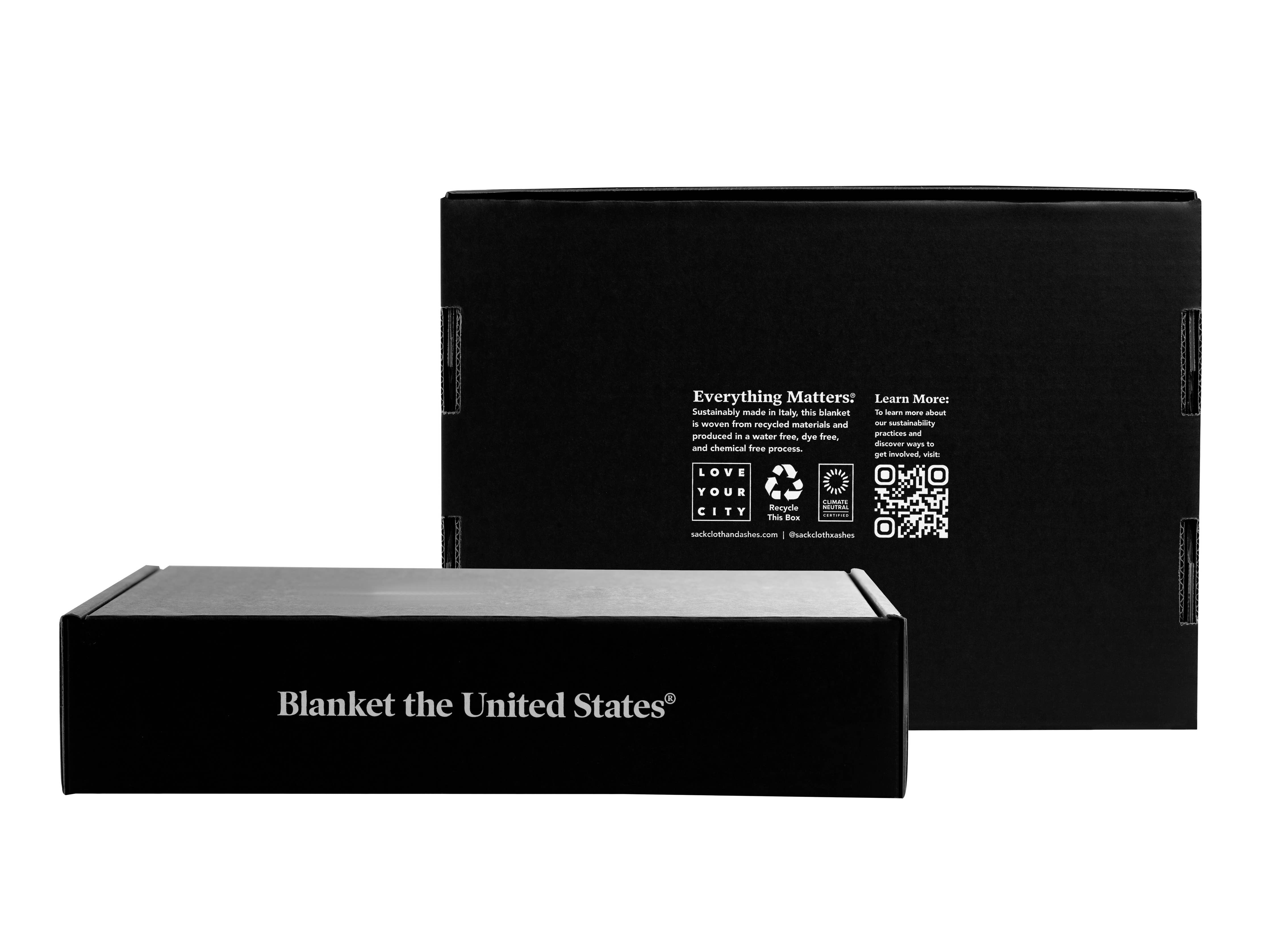 A black box with white text displaying Mountain Arctic alongside a white recycle symbol on a black background. Product promotes eco-friendly blankets made from recycled materials.