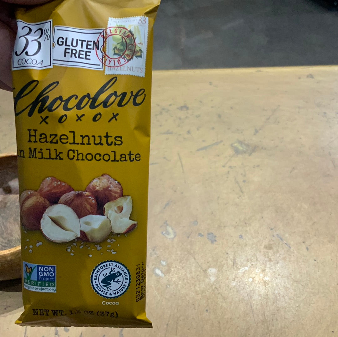 A bag of hazelnuts on a table, a yellow package with a nut image, and a logo close-up. Product: Chocolove hazelnuts milks choc.