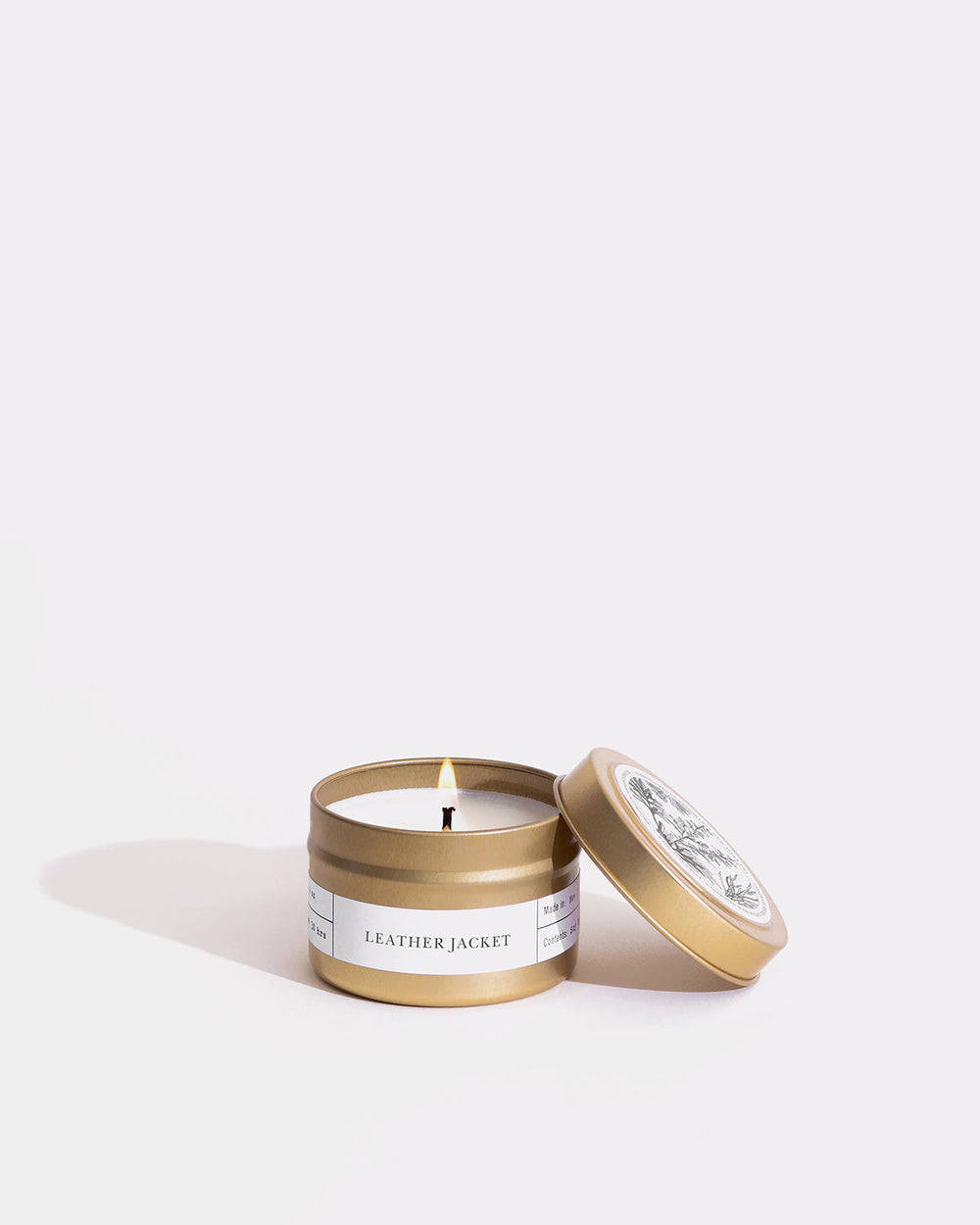 A gold container candle evoking a leather jacket with vetiver, timur pepper, cedar scents. Textured label and box. Brooklyn-made soy wax, eco-friendly, vegan, cruelty-free.