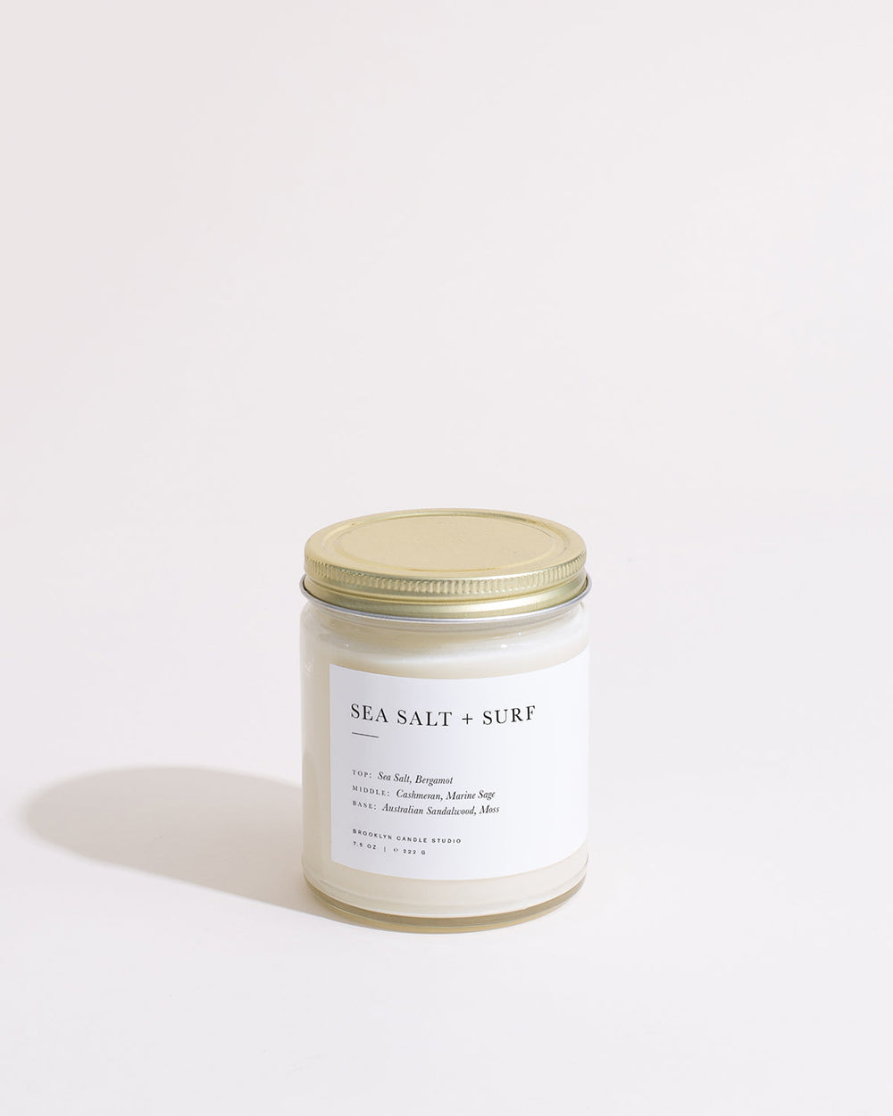 Sea Salt and Surf Minimalist Candle in white jar with gold lid, featuring sea-inspired scents like bergamot, marine sage, and sandalwood. Brooklyn Candle Studio creation, soy-based, eco-friendly, with 50-hour burn time.