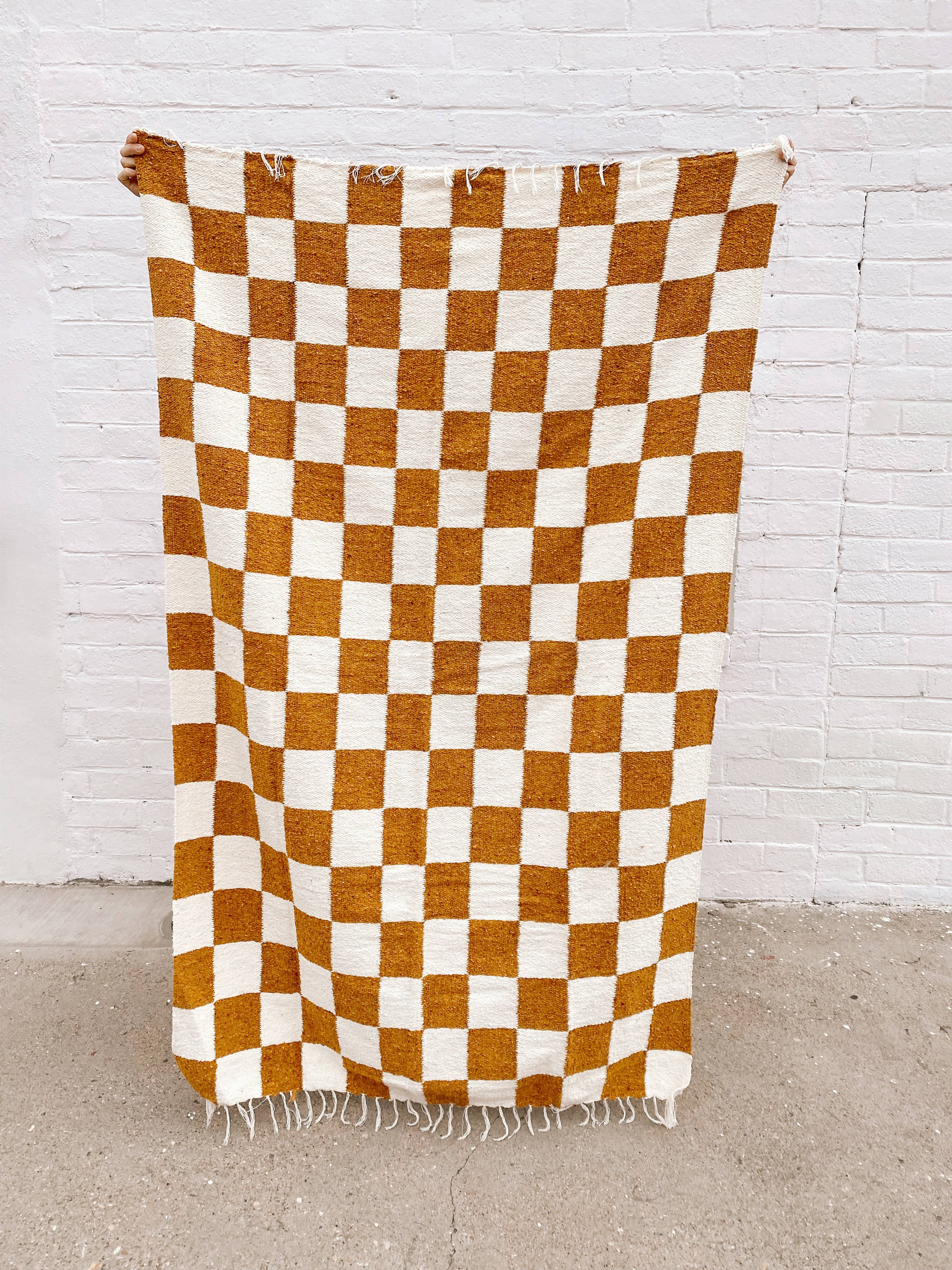 Handwoven heavyweight Laguna Throw featuring a checker pattern in mustard tones. Made from reclaimed fibers for durability and softness. Measures 83 x 52 inches, versatile as a throw or rug.