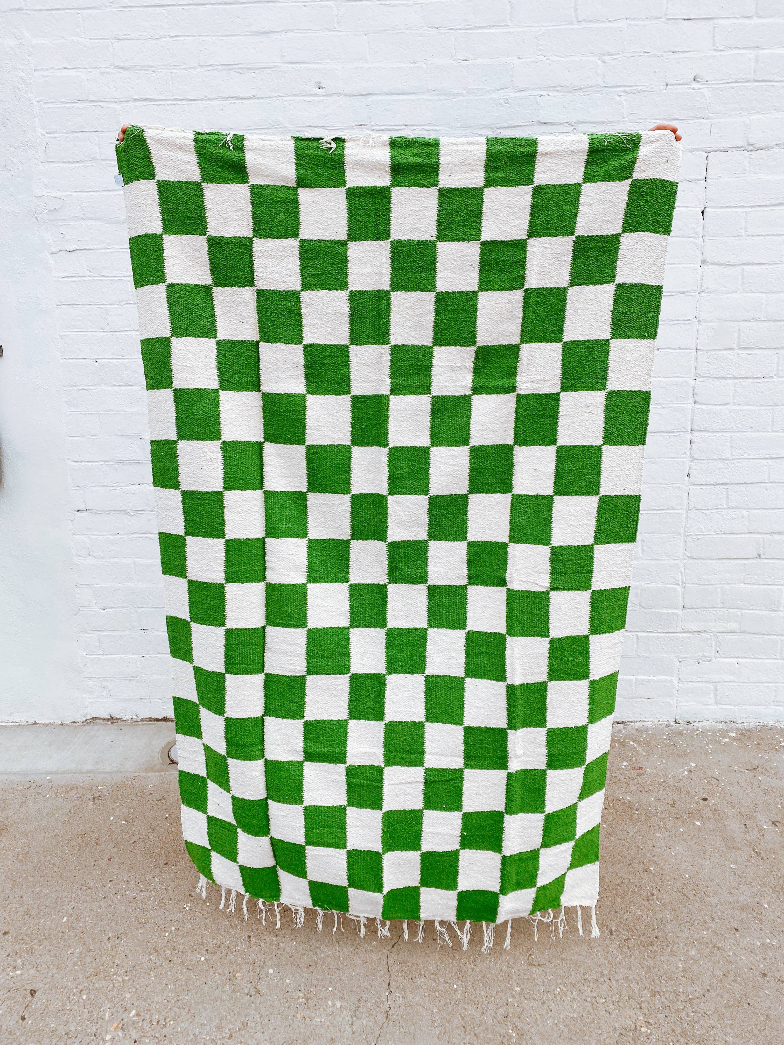 Handmade heavyweight Laguna Throw in avocado green and white checkered pattern, crafted from sustainable reclaimed fibers for versatile use as a blanket or rug.