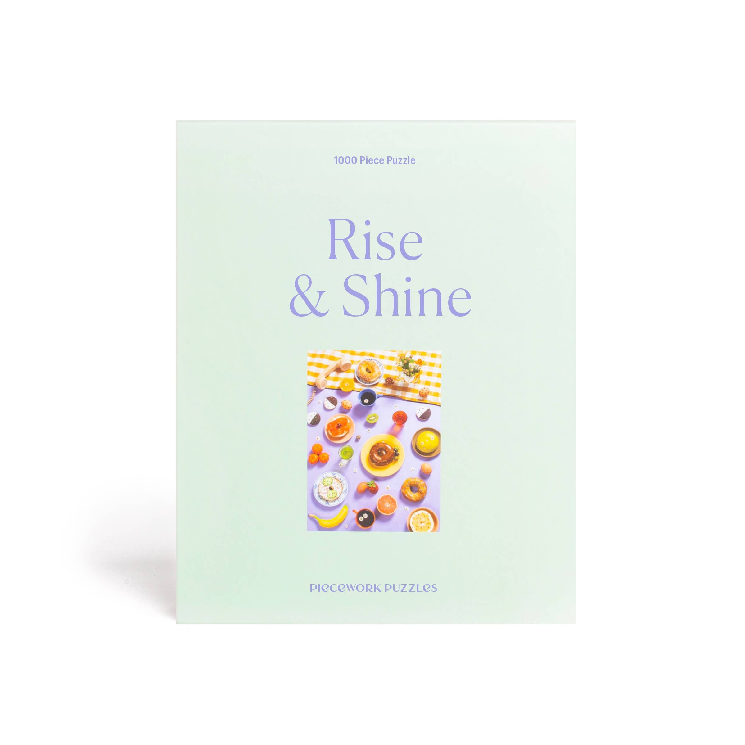 A 1000 piece Rise & Shine puzzle featuring bedazzled food items like strawberries, bagels, and olives, alongside tiny daisies. Puzzle size: 19.25 x 26.6 inches. High-quality art paper and recycled board.