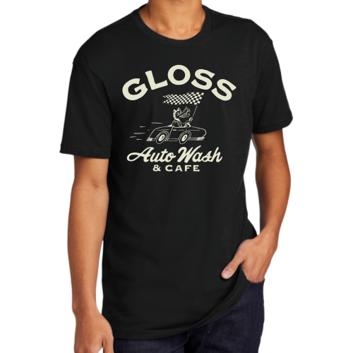 A person in a black shirt featuring white text, paired with a car and flag, embodying the Gloss Wolf Matte Gold & Black T-Shirt's stylish design.