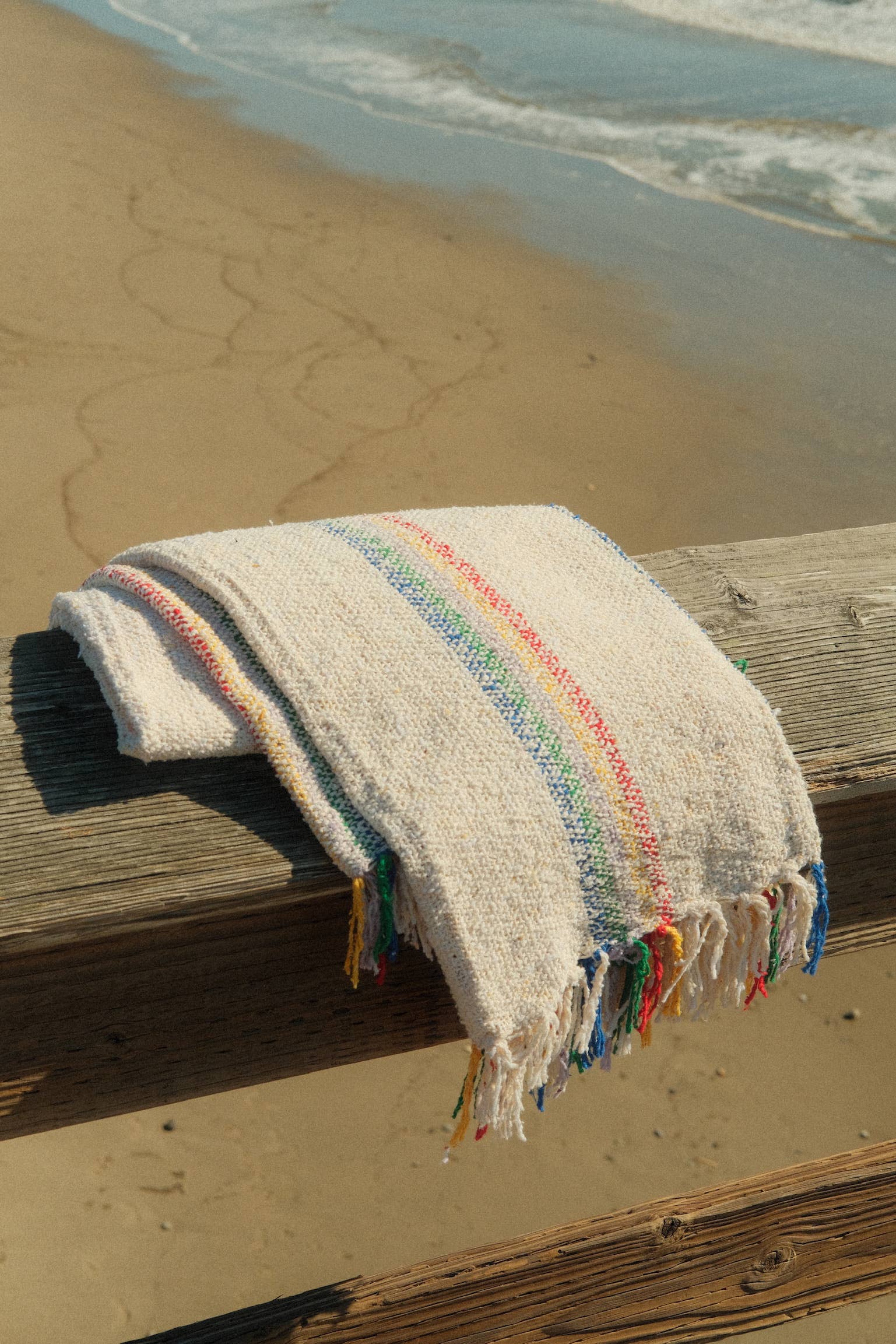 A sustainable Retro Rainbow Cream throw blanket made from reclaimed fibers, perfect for home or outdoor use. Measures 73 x 48 inches. Designed in California, artisan-made in Mexico.