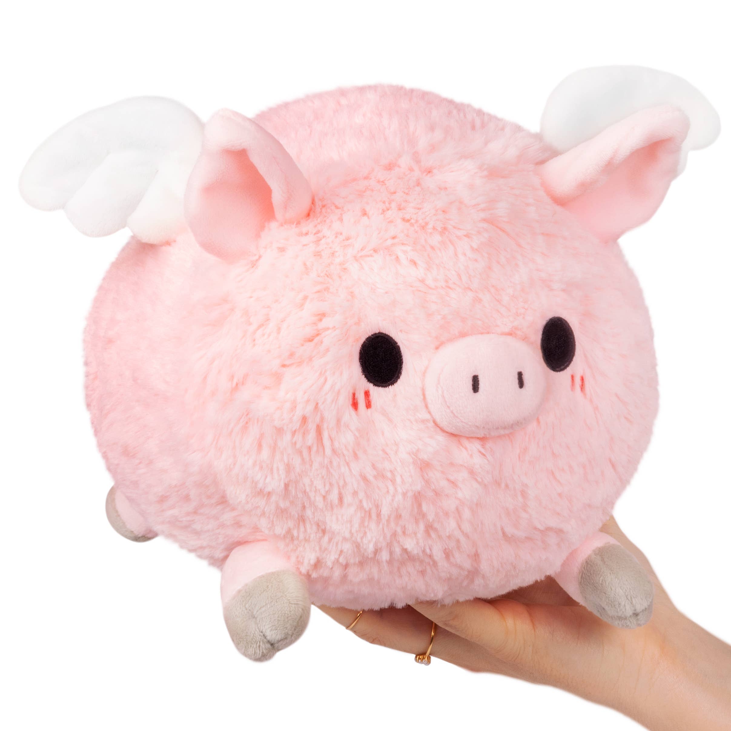 A hand holds a pink stuffed Flying Piglet toy, featuring cute ears and a fluffy body. Product measures 6.5 x 9.5 x 7 inches, made of polyester fiber for ages 3 and up.