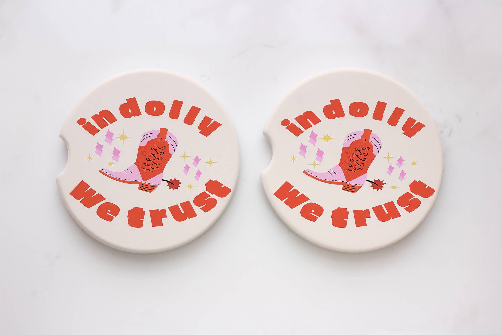 Pair of absorbent Dolly Parton car coasters with cowboy boot design. Printed on durable cloth top with rubber backing for long-lasting use.