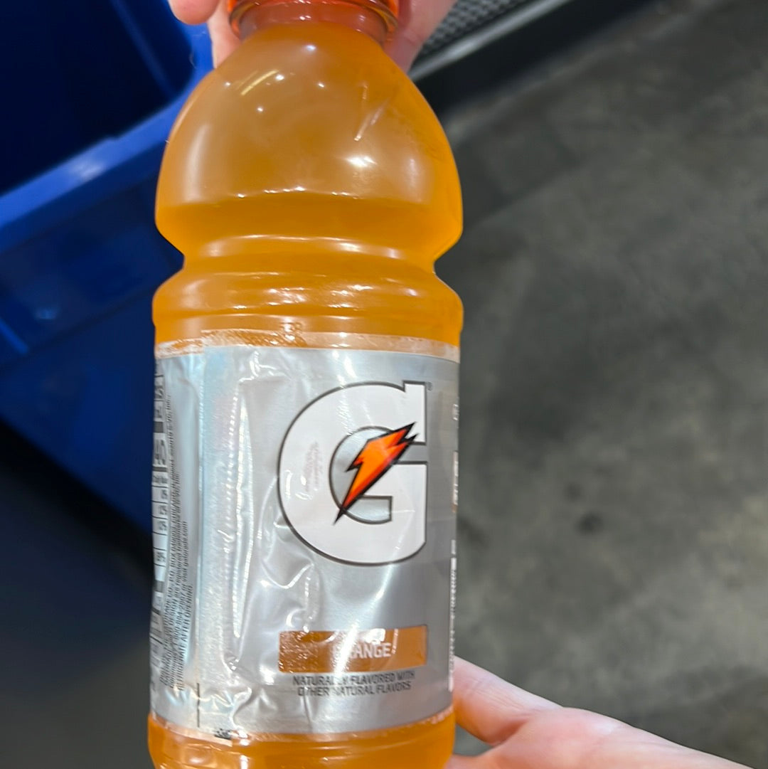 A hand holding Gatorade Orange bottle, featuring a lightning bolt logo. Close-up of the beverage container.