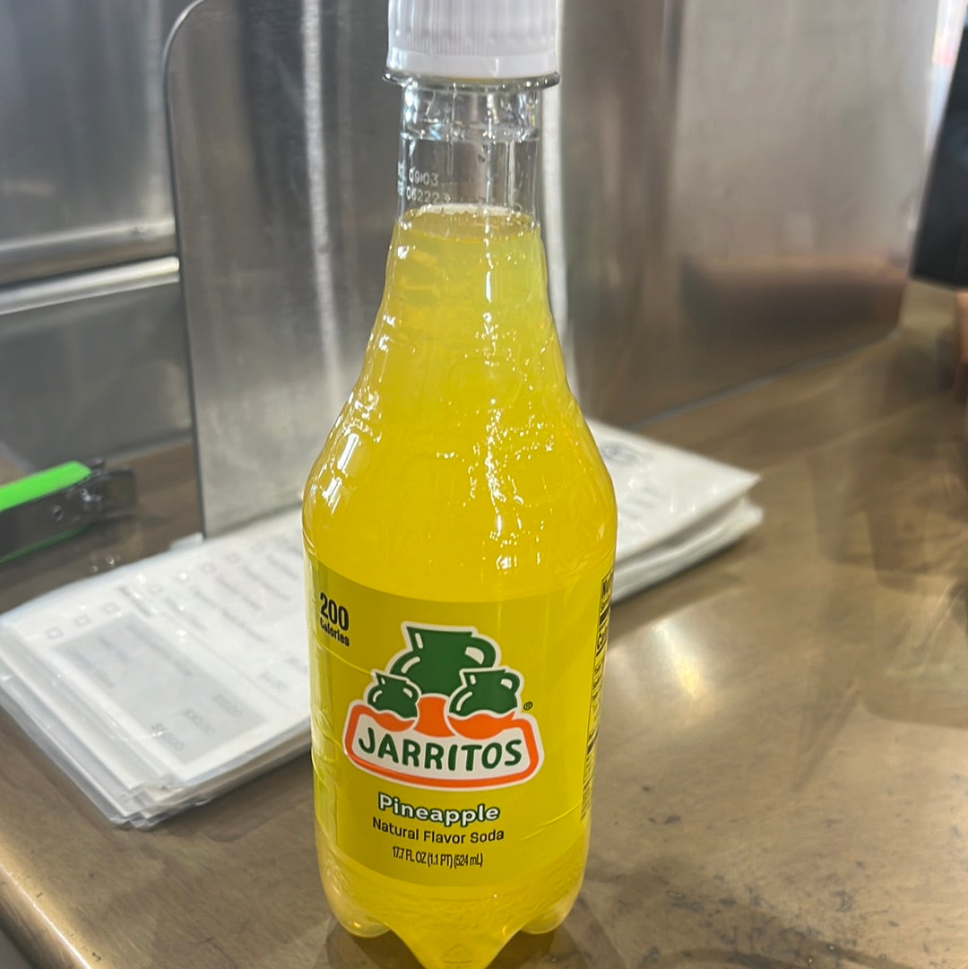 A bottle of Jarritos piña, a yellow soft drink with green and orange accents, representing a refreshing pineapple flavor.