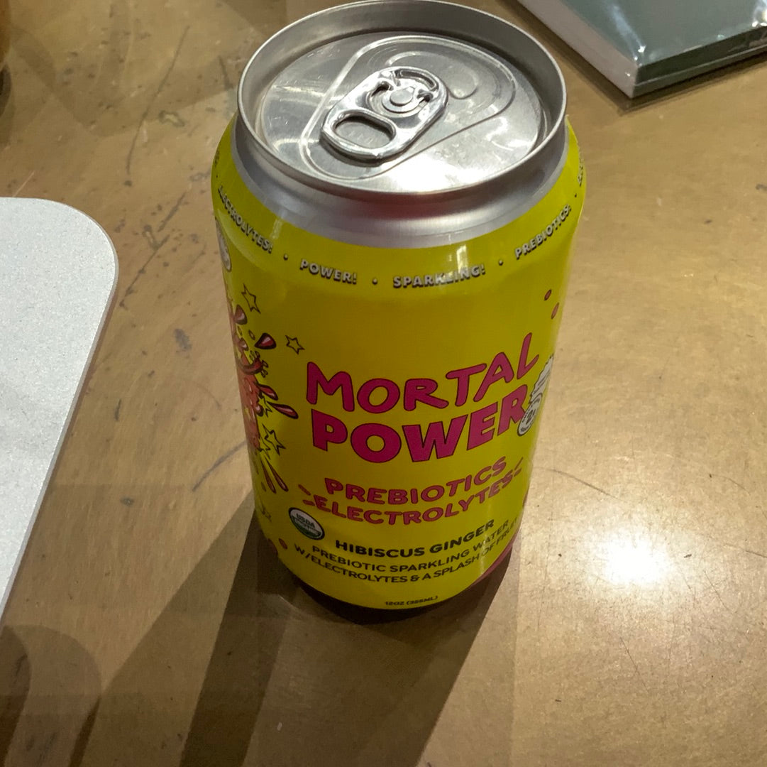 A yellow aluminum can of Mortal Kombucha Hibiscus Ginger Power on a table, featuring a pop top and pink text.