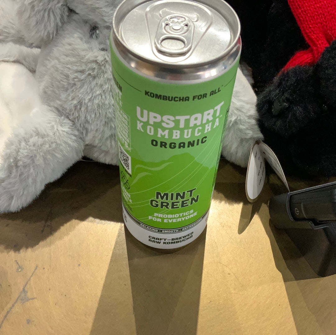 A green Upstart Kombucha can, featuring a mint green label, on a table.