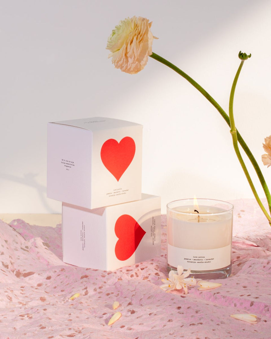 A soy wax Love Potion candle in a textured box with a red heart, jasmine, lavender, and mandarin scents. Made in Brooklyn, eco-friendly, vegan, cruelty-free.